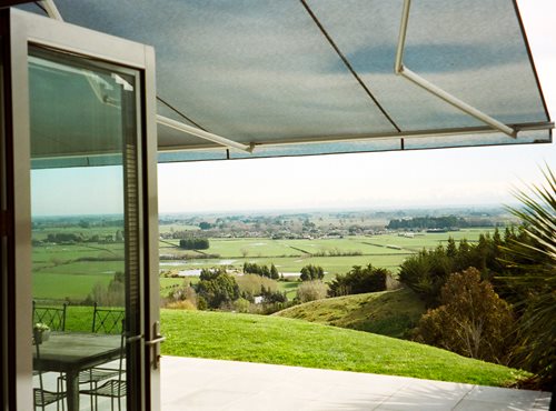 Euro Retractable awning open over outside sitting area looking out at farm land